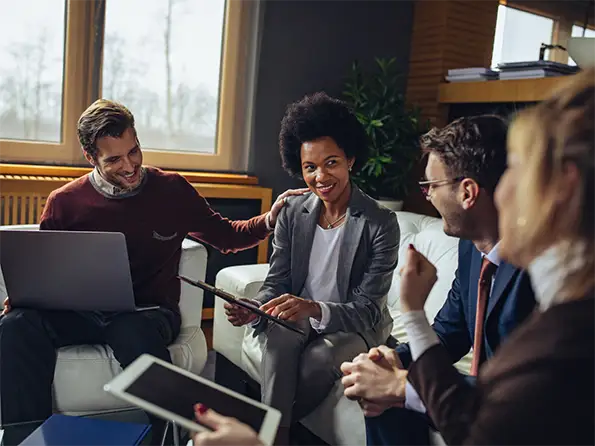 Group of people sitting with tablets and laptops open discussing work