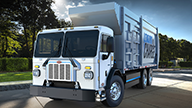 Peterbilt Model 520EV Electric White Truck with Garbage / Refuse Collection Body on Treelined Suburban Street - Thumbnail
