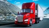 Peterbilt Model 579 Class 8 Heavy Duty Day Cab hauling a box trailer on curved road in front of snow covered mountains - Thumbnail
