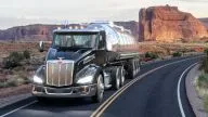 Peterbilt Model 579 Class 8 Heavy Duty Day Cab hauling a tanker trailer on curved road in front of red rocks - Thumbnail
