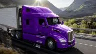Peterbilt Model 579 UltraLoft Class 8 Heavy Duty Sleeper Cab hauling a box trailer on curved road in front of mountains and valley - Thumbnail